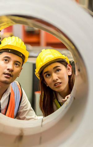 two workers looking through a pipe - Energy & Heavy Industry